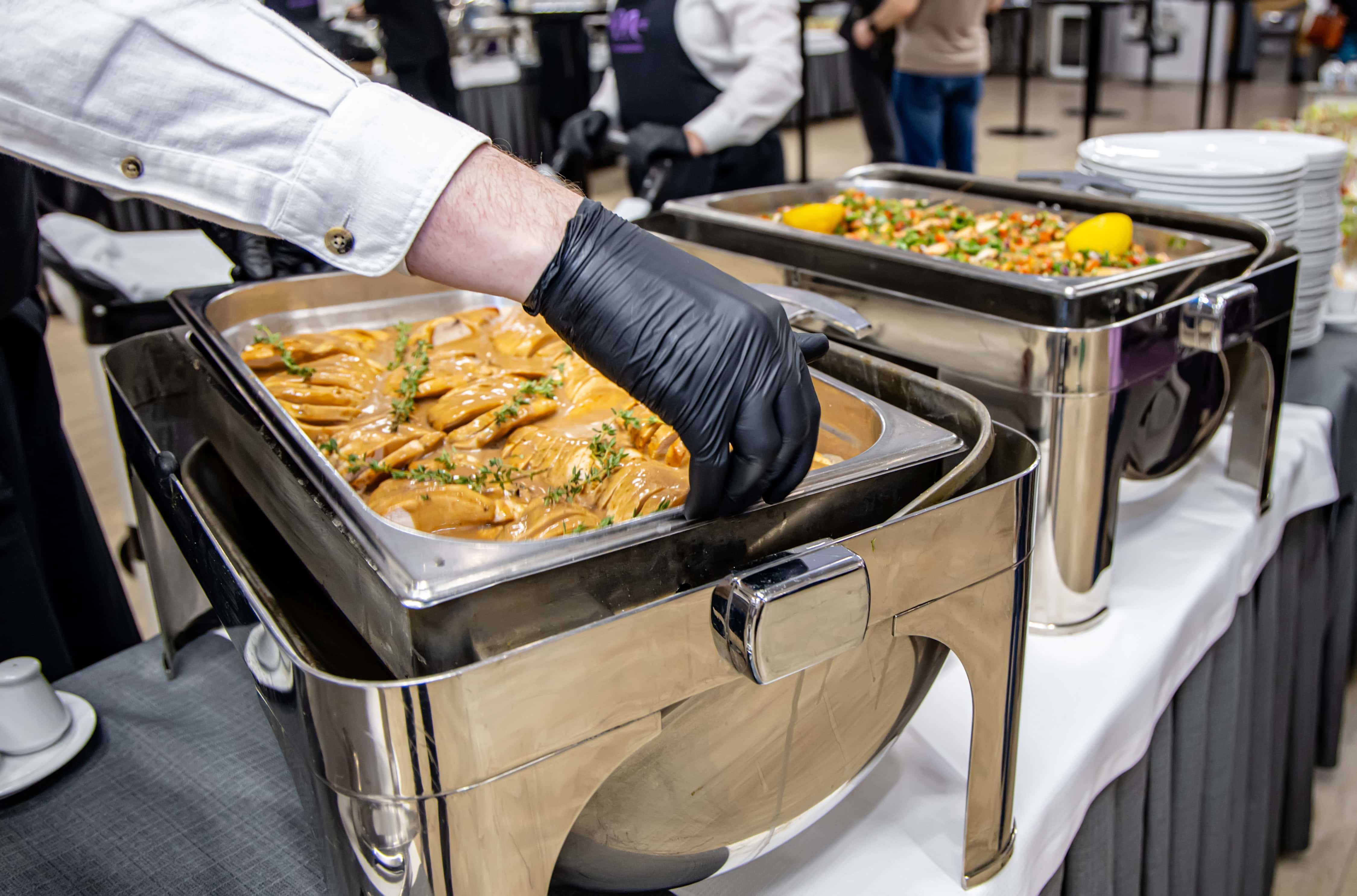 Camarero sirviendo un plato caliente en un buffet de empresa