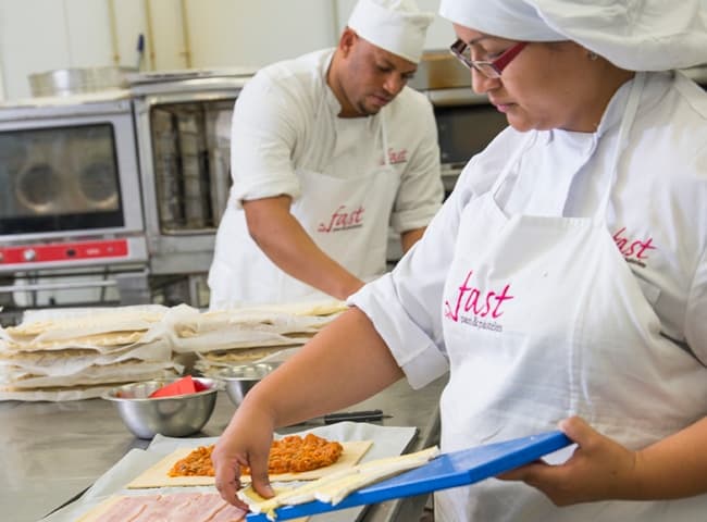 Dos cocineros del equipo preparando empanadas en el obrador