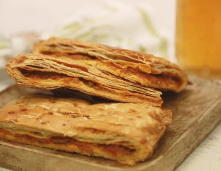 Empanada de hojaldre artesana cortada sobre tabla de madera