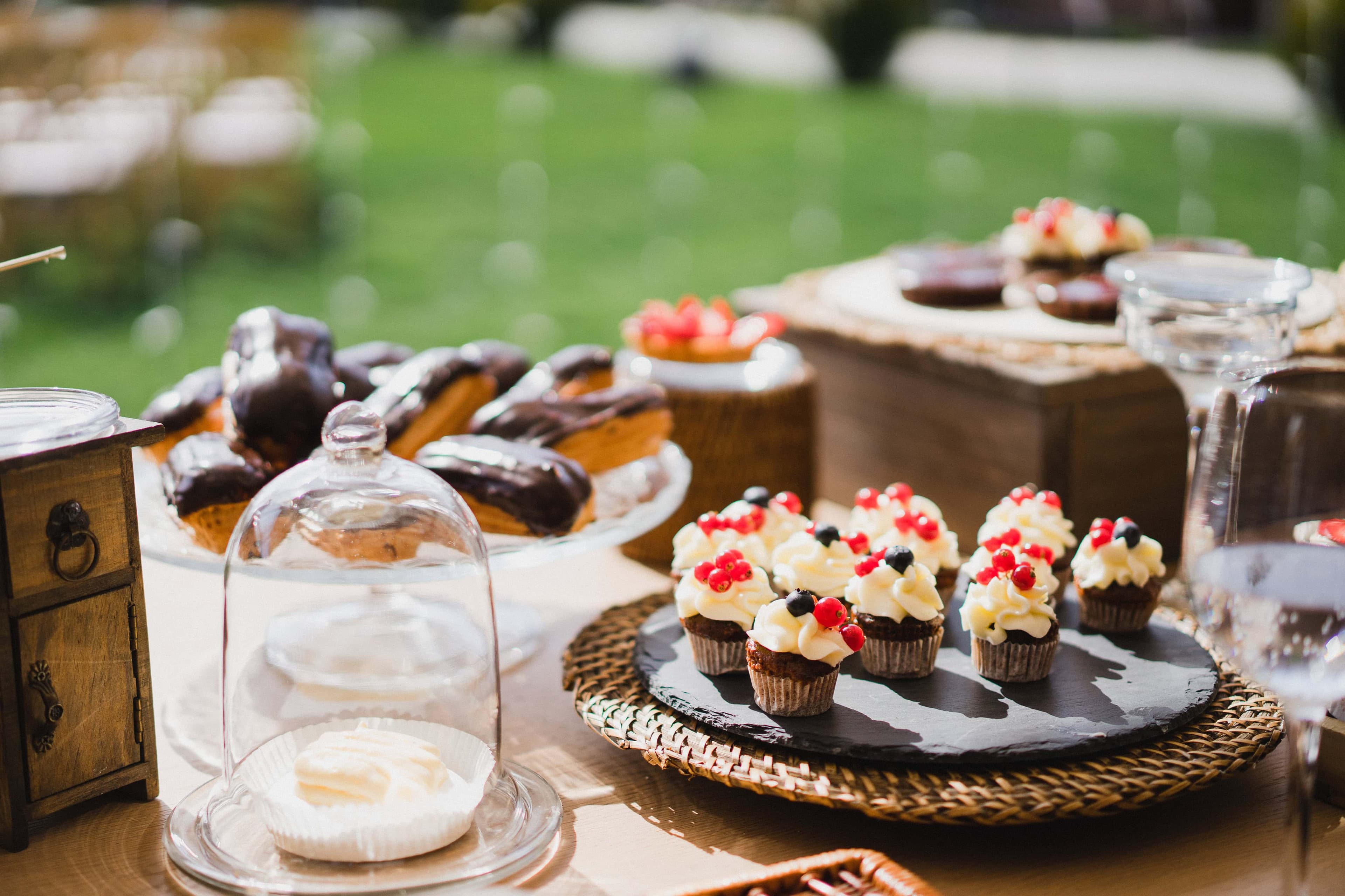 Mesa dulce con eclairs y mini cupcakes en un evento al aire libre