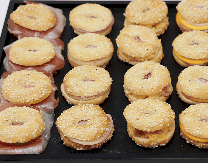 Bandeja de mini bagels de sésamo rellenos de jamón y queso